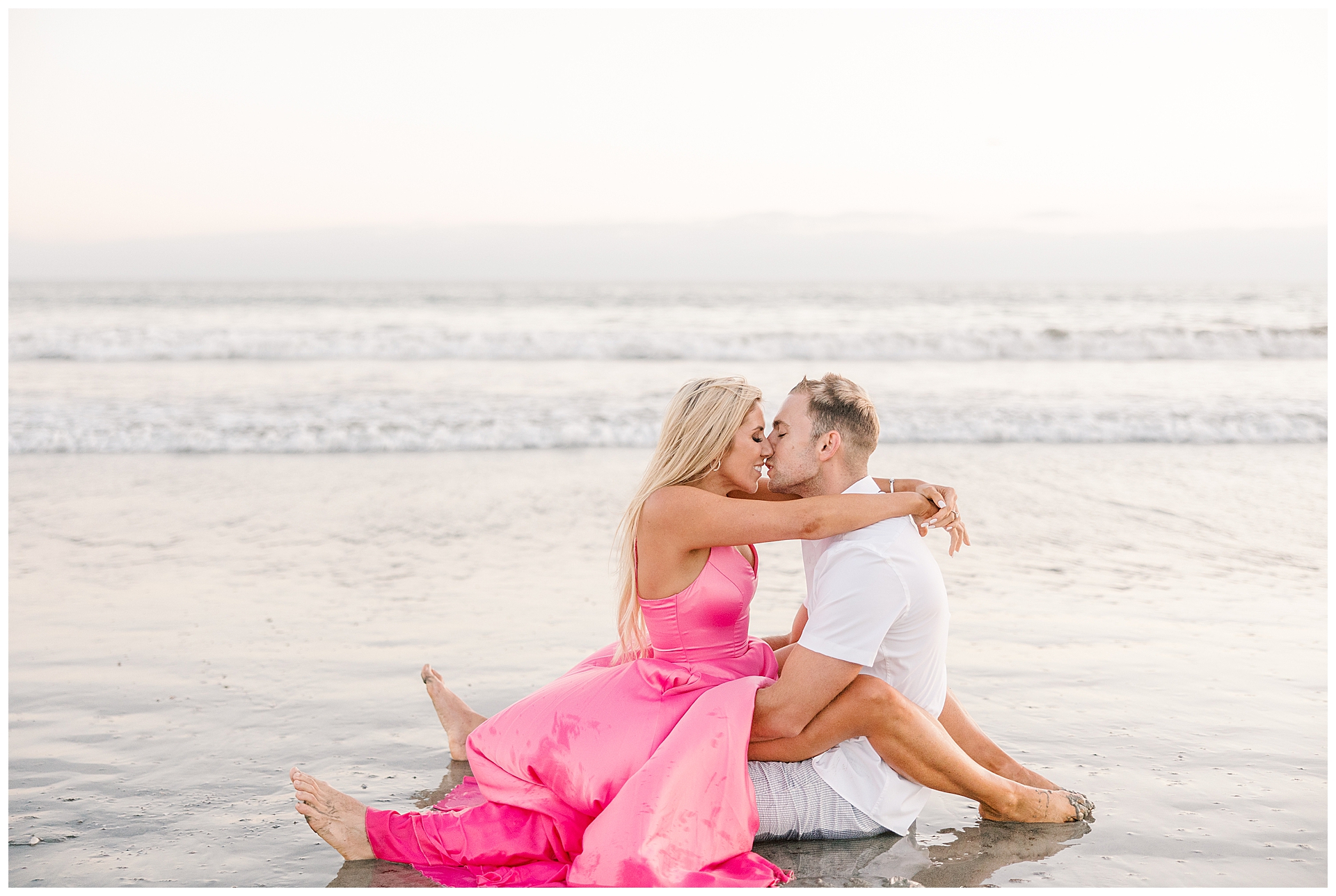 Couple sitting in the Pacific Ocean sharing a kiss at their Coronado Beach engagement session