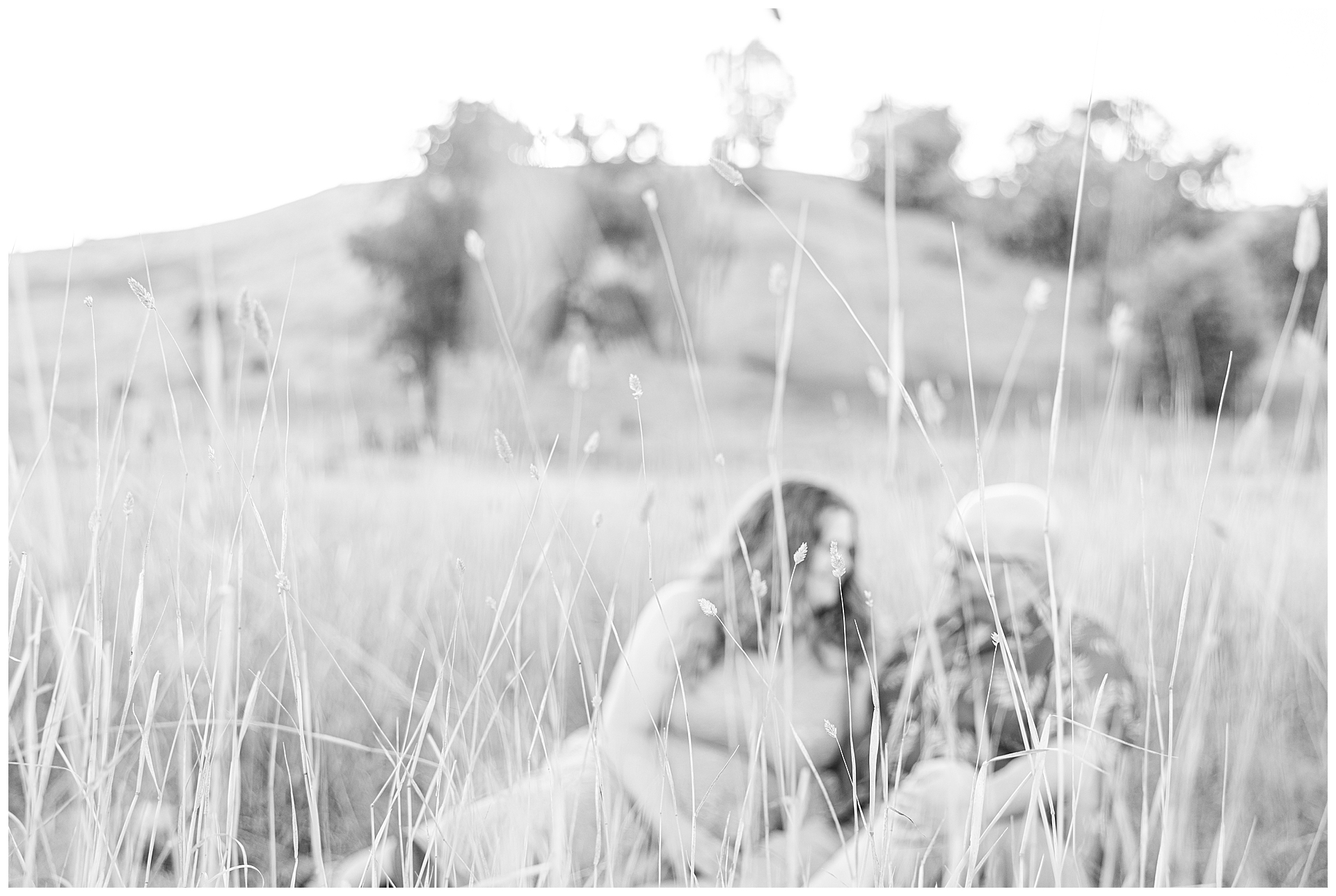 San Jose Engagement Shoot in Santa Teresa County Park; Couple sitting in the grass with the rolling hills behind them.